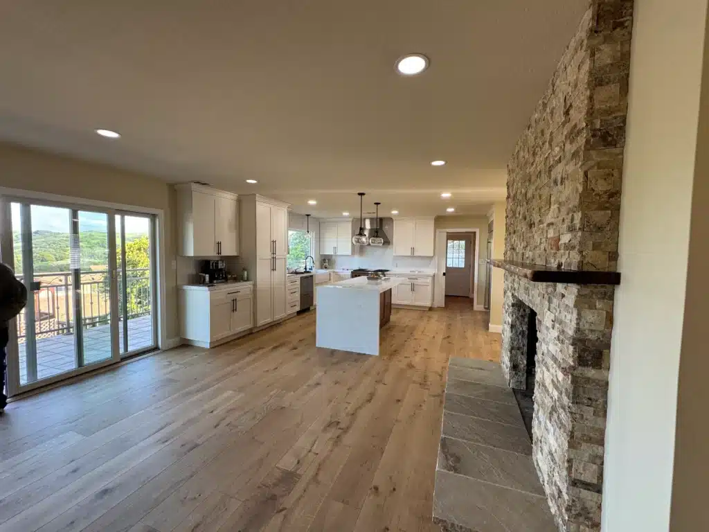 Newly built white kitchen with wooden floors and stone fireplace