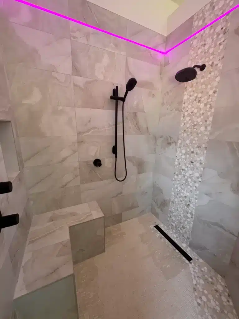 Curb-less walk-in shower with dual matte black fixtures and mosaic feature wall in Los Angeles remodel.