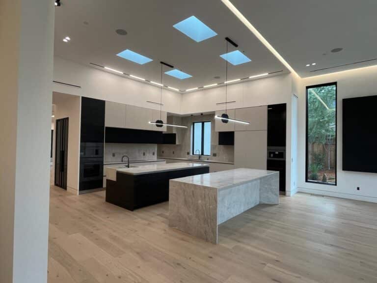 white and navy kitchen with large marble island in open floor space