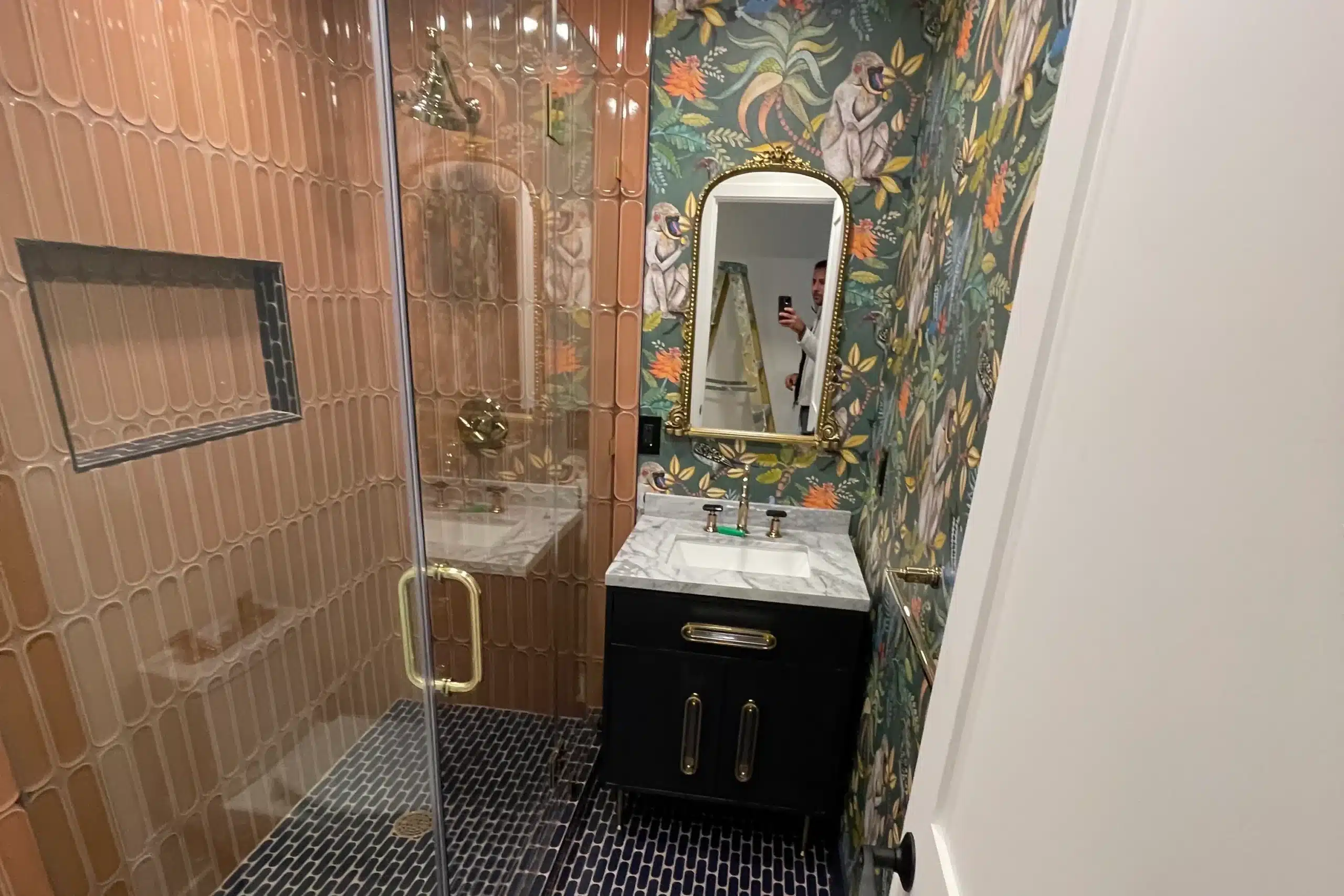 Stylish bathroom remodel with walk-in shower, patterned wallpaper, and modern vanity.
