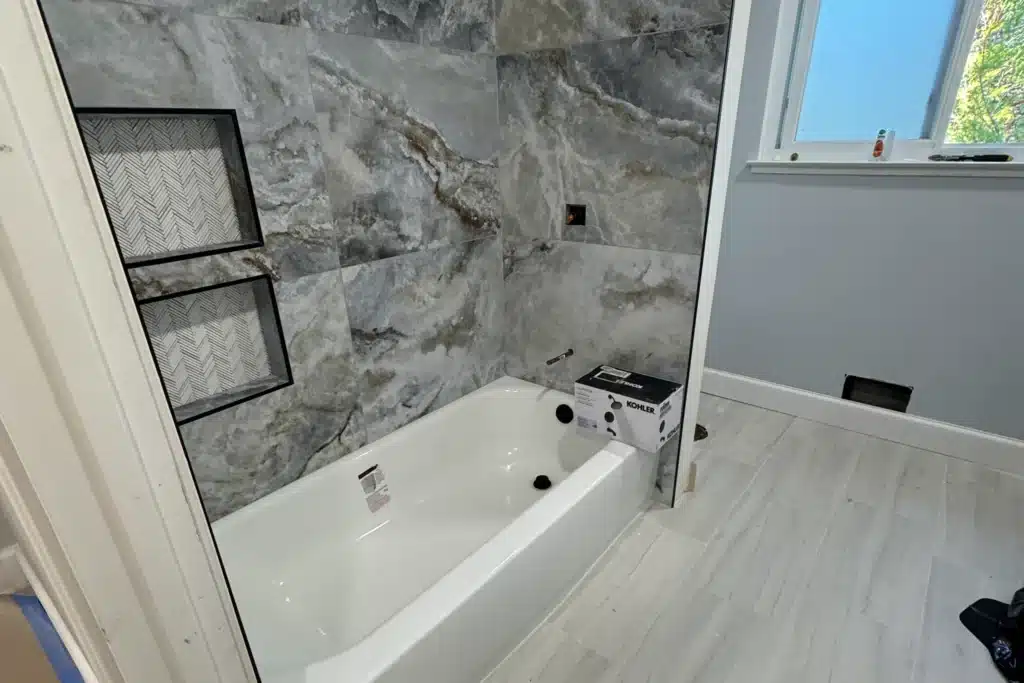 Bathroom remodel featuring porcelain tile and recessed storage niches for improved function and appearance.