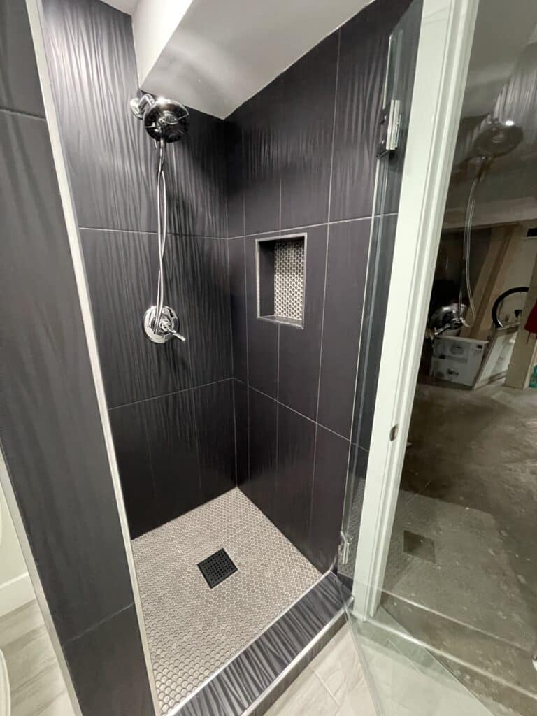 Modern shower renovation with dark tile and recessed niche in Los Angeles.