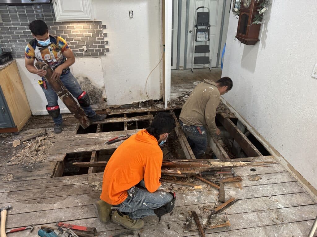 Three men removing the wooden floors of a house during remodeling