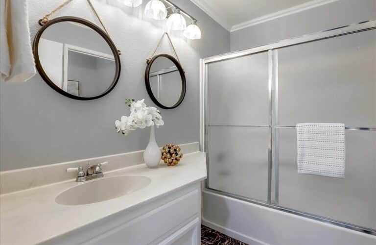 Light and open bathroom with white elements and dual mirrors
