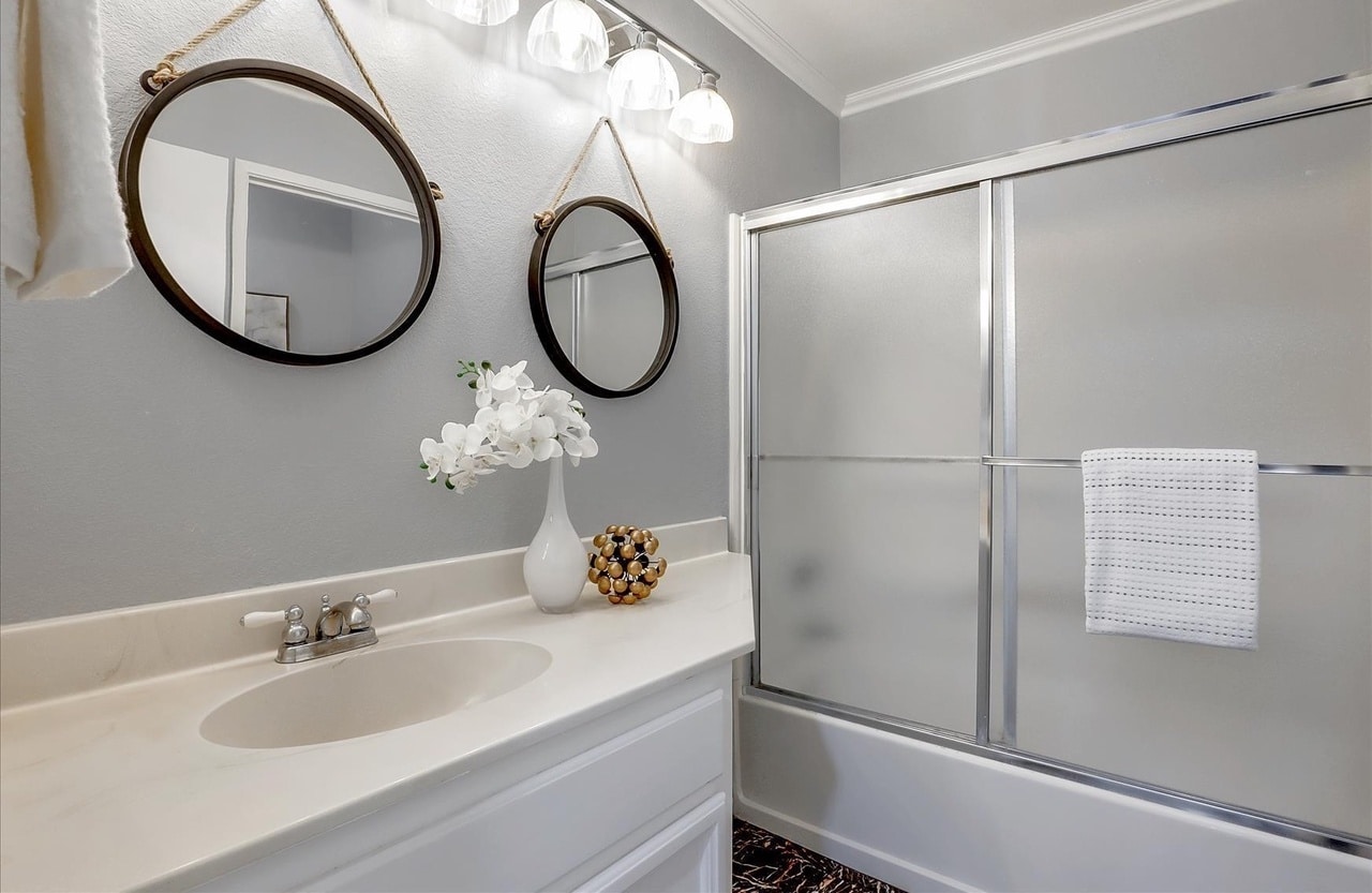 Light and open bathroom with white elements and dual mirrors