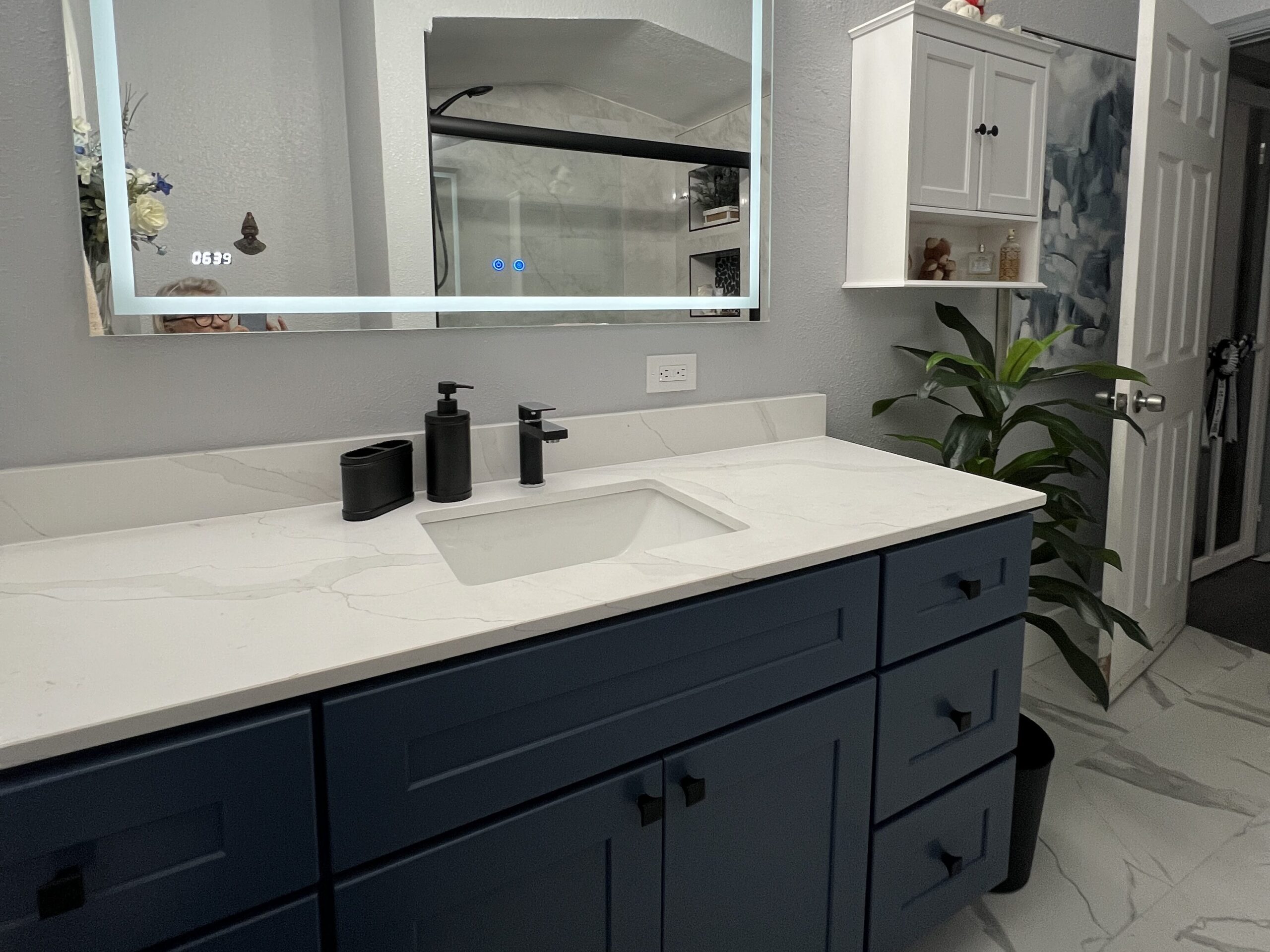 bathroom with white marble counter top and navy cupboards