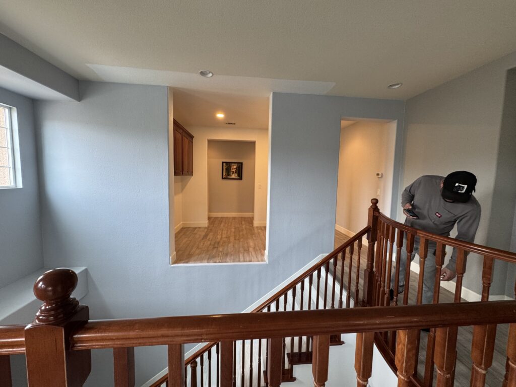 Second-story residential landing with blue walls and dark wood banister during an initial home addition structural site assessment.