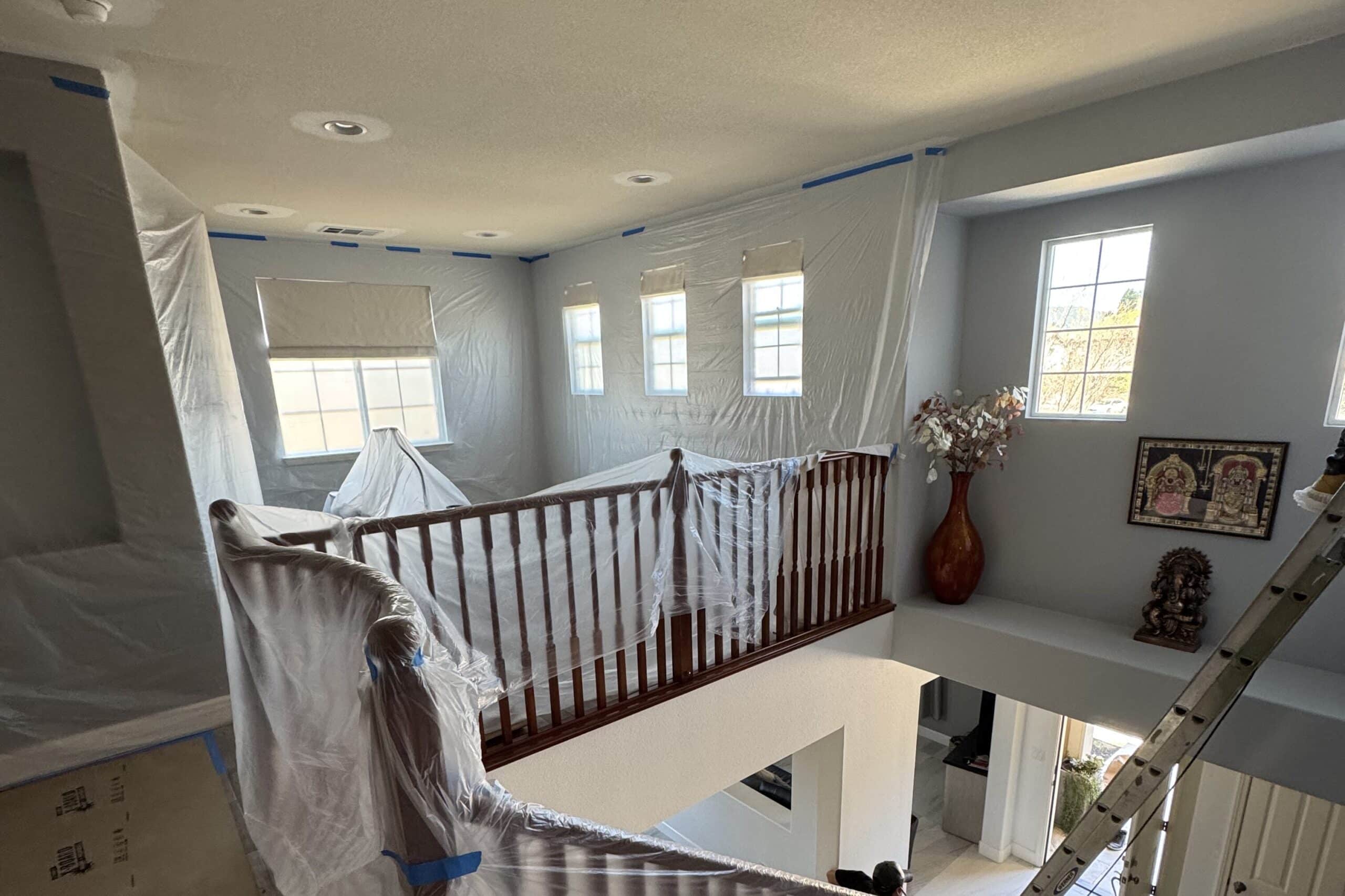 Upper-floor home addition prepped for construction with plastic sheeting covering walls, windows, and banisters.