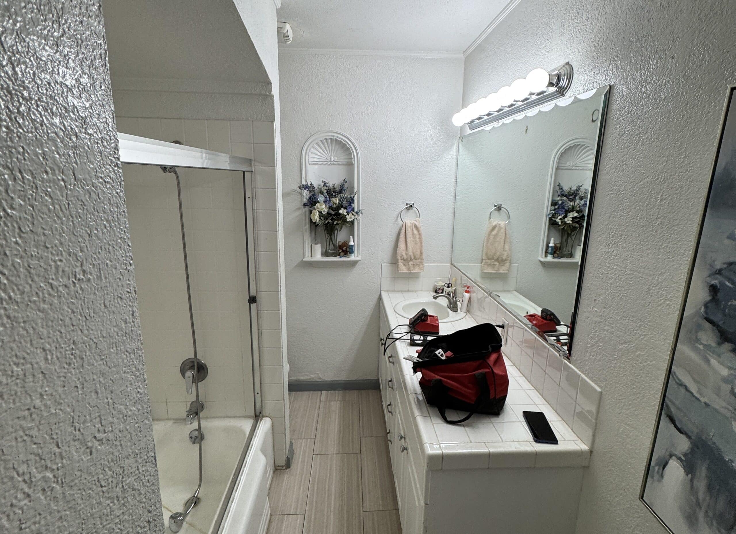 newly renovated white bathroom in Los Angeles with a tub and dual sinks with large mirror