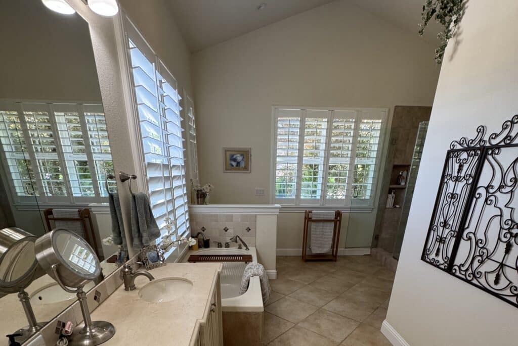 Big bathroom with large windows, big mirror and a tub.